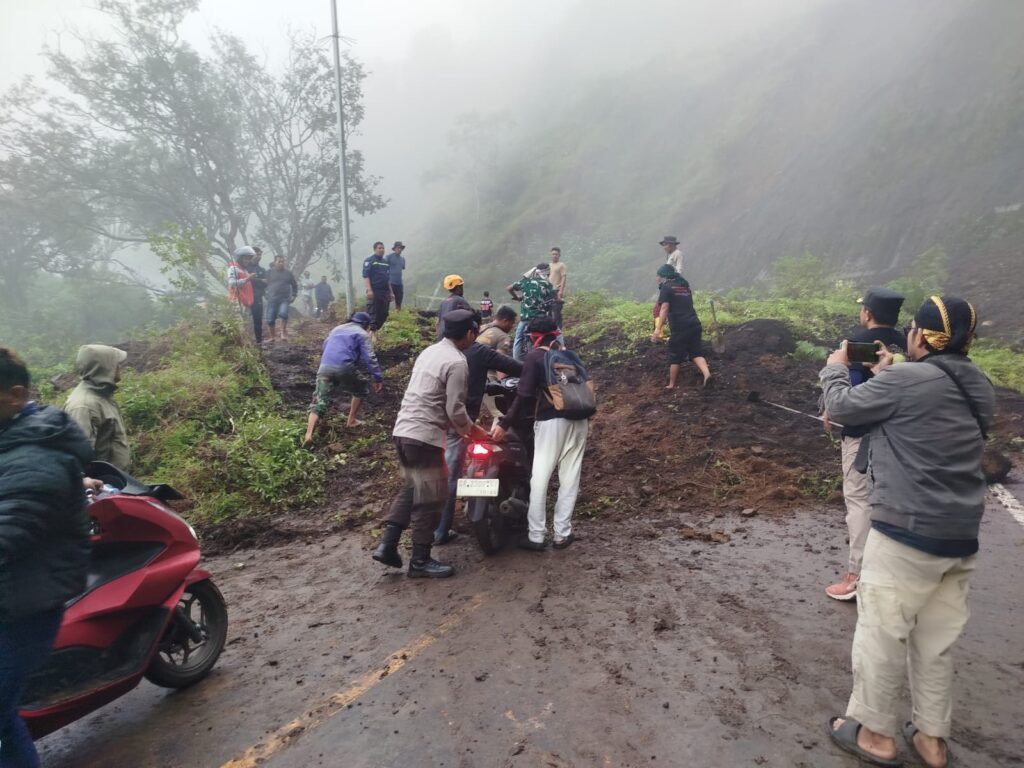 tim gabungan membantu warga melewati jalan yg tertutup longsor